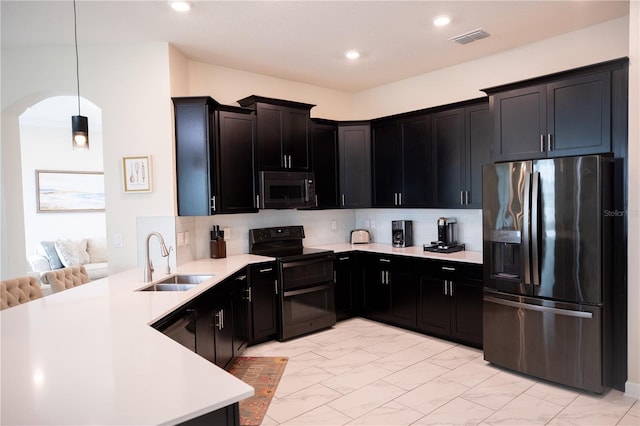 kitchen featuring hanging light fixtures, kitchen peninsula, sink, tasteful backsplash, and stainless steel appliances