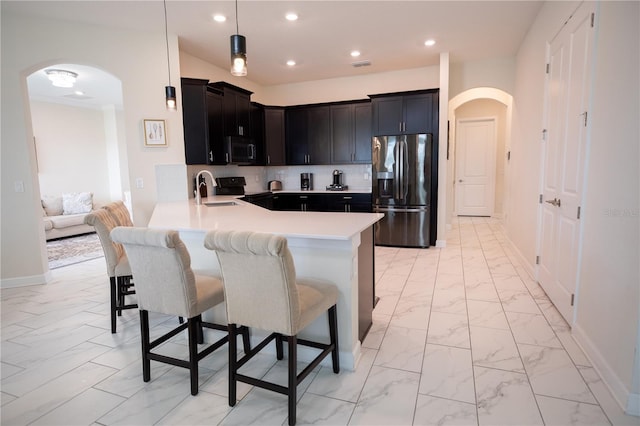 kitchen featuring a kitchen breakfast bar, stainless steel appliances, kitchen peninsula, and tasteful backsplash