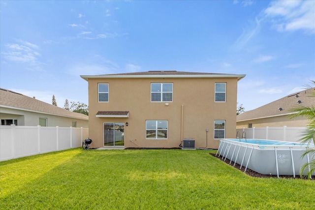 rear view of house with a fenced in pool and a yard