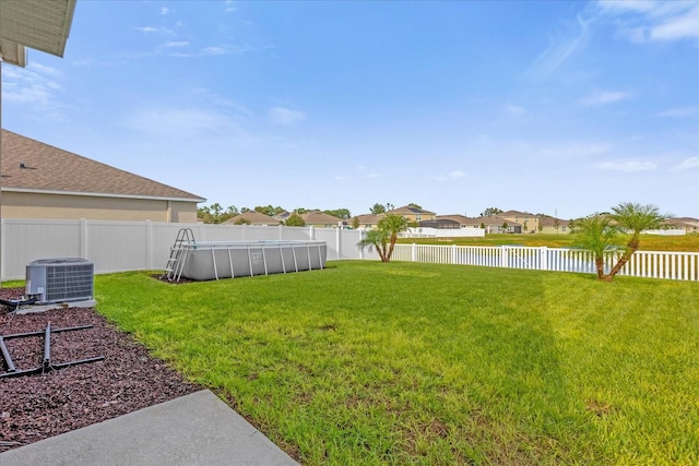 view of yard with central air condition unit and a fenced in pool