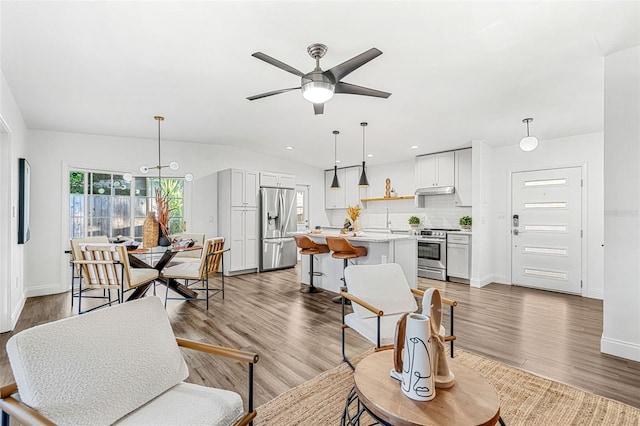 living room featuring lofted ceiling, ceiling fan, and light hardwood / wood-style floors