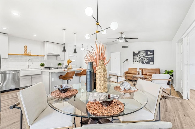 dining area featuring sink, light wood-type flooring, and ceiling fan