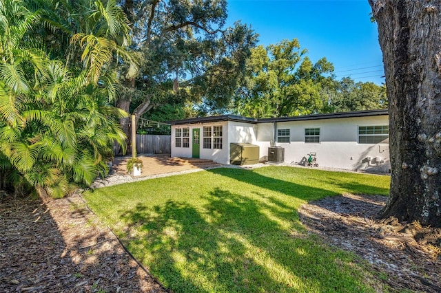 rear view of property featuring central AC unit and a lawn