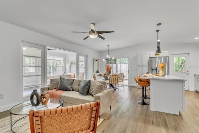 living room featuring light hardwood / wood-style floors, a wealth of natural light, and ceiling fan with notable chandelier