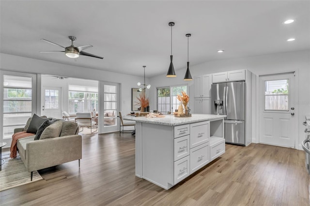 kitchen featuring light stone counters, pendant lighting, a center island, stainless steel refrigerator with ice dispenser, and white cabinetry