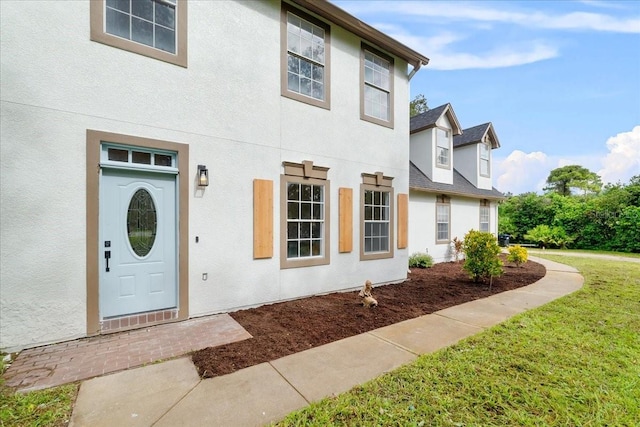property entrance featuring a lawn and stucco siding