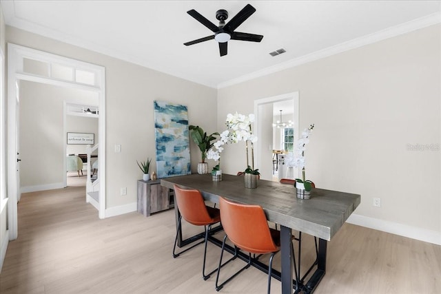 dining space with ceiling fan with notable chandelier, light hardwood / wood-style flooring, and crown molding