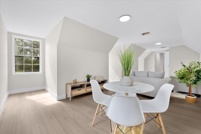 dining space with visible vents, baseboards, vaulted ceiling, and wood finished floors