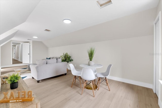 dining area featuring visible vents, light wood-style flooring, baseboards, and lofted ceiling