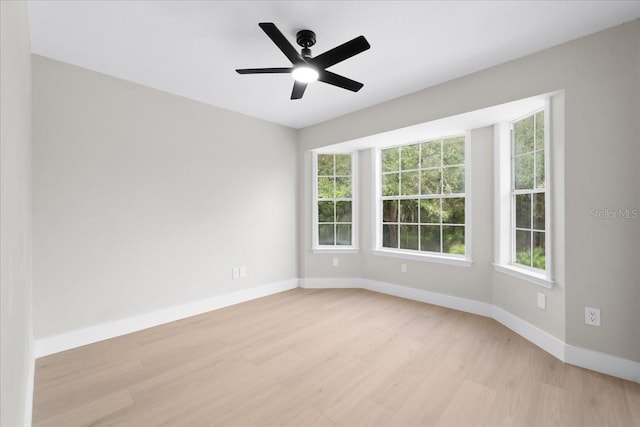 spare room with light wood-style flooring, baseboards, a ceiling fan, and plenty of natural light