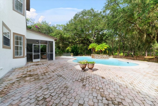 pool with a sunroom, a patio area, a ceiling fan, and fence