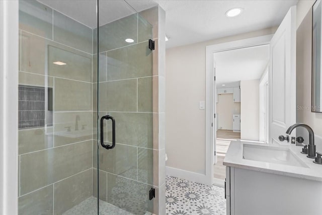 bathroom featuring a stall shower, baseboards, and vanity