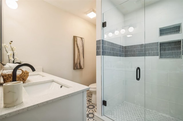 bathroom featuring toilet, double vanity, a shower stall, and visible vents