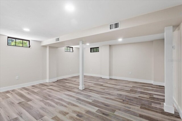 below grade area with wood finished floors, visible vents, and baseboards