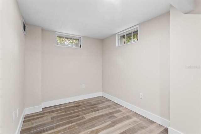 basement featuring a healthy amount of sunlight, visible vents, baseboards, and wood finished floors