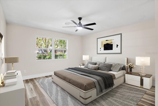 bedroom with ceiling fan, wood finished floors, and baseboards