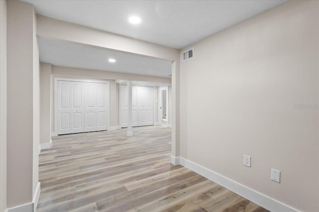 corridor with light wood finished floors, baseboards, visible vents, and recessed lighting