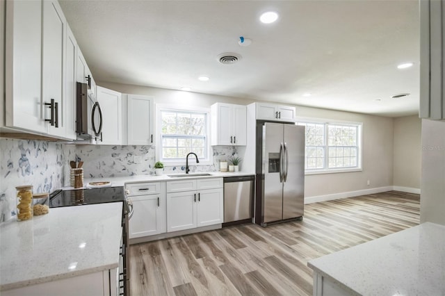 kitchen with light wood finished floors, visible vents, backsplash, appliances with stainless steel finishes, and a sink