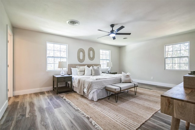 bedroom featuring baseboards, visible vents, ceiling fan, and wood finished floors