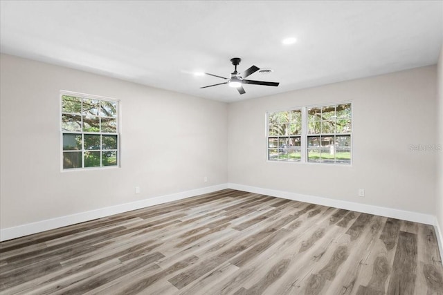 spare room with baseboards, wood finished floors, a ceiling fan, and a healthy amount of sunlight