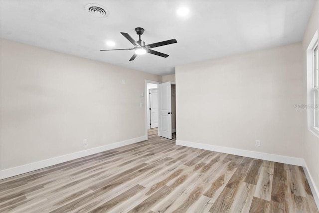 spare room featuring light wood-type flooring, visible vents, ceiling fan, and baseboards