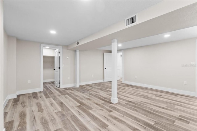 finished below grade area featuring light wood-style flooring, recessed lighting, visible vents, and baseboards