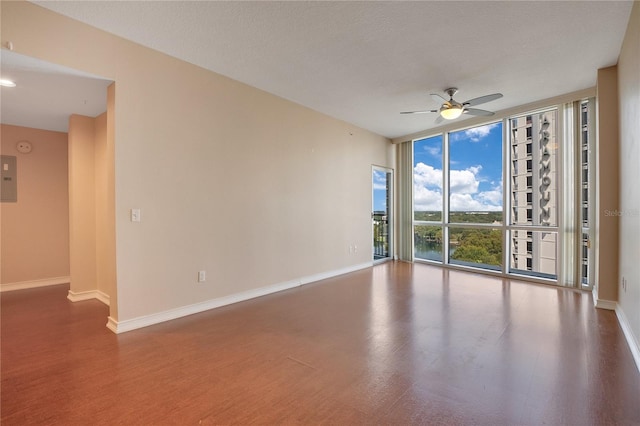 unfurnished room with ceiling fan, wood-type flooring, floor to ceiling windows, electric panel, and a textured ceiling