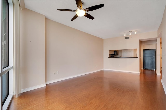 unfurnished living room featuring ceiling fan, dark hardwood / wood-style floors, and a healthy amount of sunlight