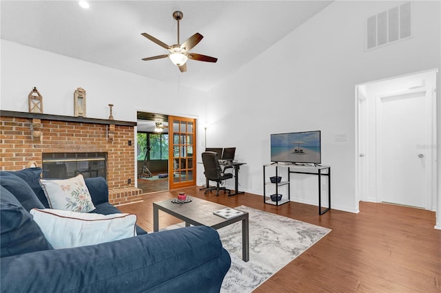 living room featuring high vaulted ceiling, wood-type flooring, ceiling fan, and a fireplace