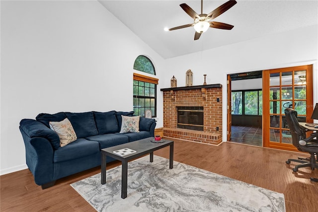 living room with high vaulted ceiling, hardwood / wood-style floors, ceiling fan, and a brick fireplace