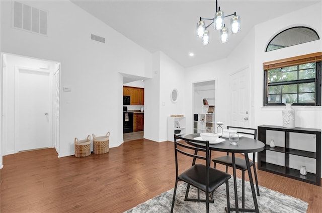 dining area with an inviting chandelier, dark wood-type flooring, and high vaulted ceiling