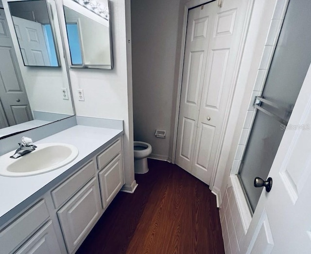 full bathroom with shower / bath combination with glass door, toilet, vanity, and hardwood / wood-style flooring