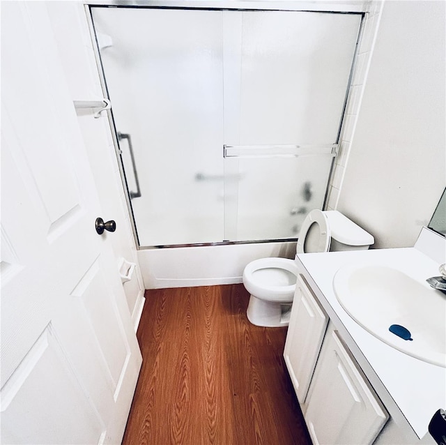 full bathroom featuring vanity, toilet, wood-type flooring, and enclosed tub / shower combo