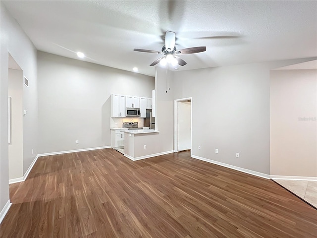 unfurnished living room with ceiling fan, dark wood-type flooring, and a textured ceiling