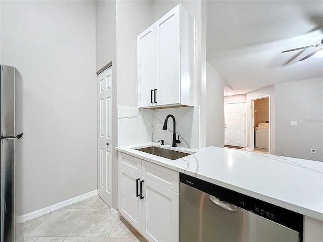 kitchen featuring appliances with stainless steel finishes, washer / clothes dryer, white cabinets, ceiling fan, and sink