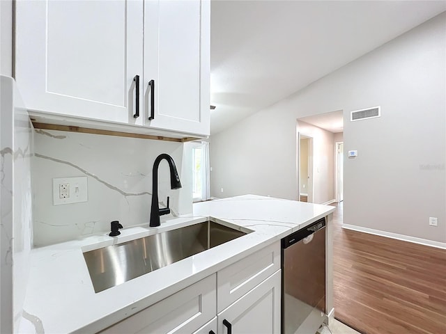 kitchen with white cabinets, dishwasher, light stone countertops, hardwood / wood-style floors, and sink