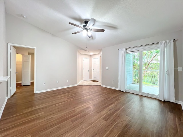 unfurnished room featuring ceiling fan, vaulted ceiling, a textured ceiling, and dark wood-type flooring