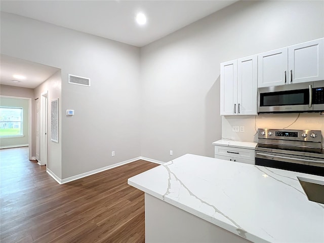 kitchen with light stone countertops, appliances with stainless steel finishes, dark wood-type flooring, and white cabinetry