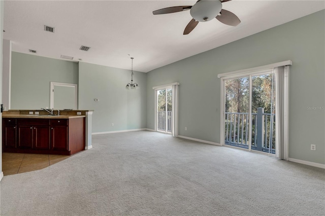 unfurnished living room featuring light carpet, sink, and ceiling fan with notable chandelier