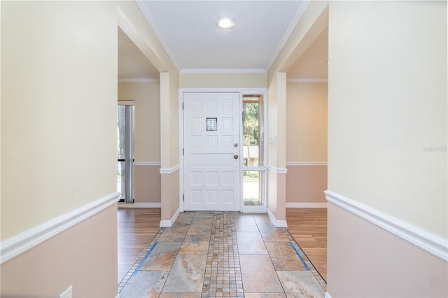 entrance foyer featuring a textured ceiling, light hardwood / wood-style floors, and ornamental molding