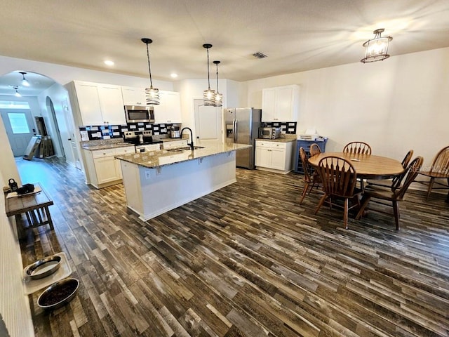 kitchen with appliances with stainless steel finishes, a kitchen island with sink, dark hardwood / wood-style floors, and white cabinets