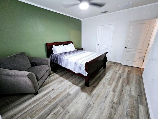 bedroom with ceiling fan, crown molding, and light hardwood / wood-style floors