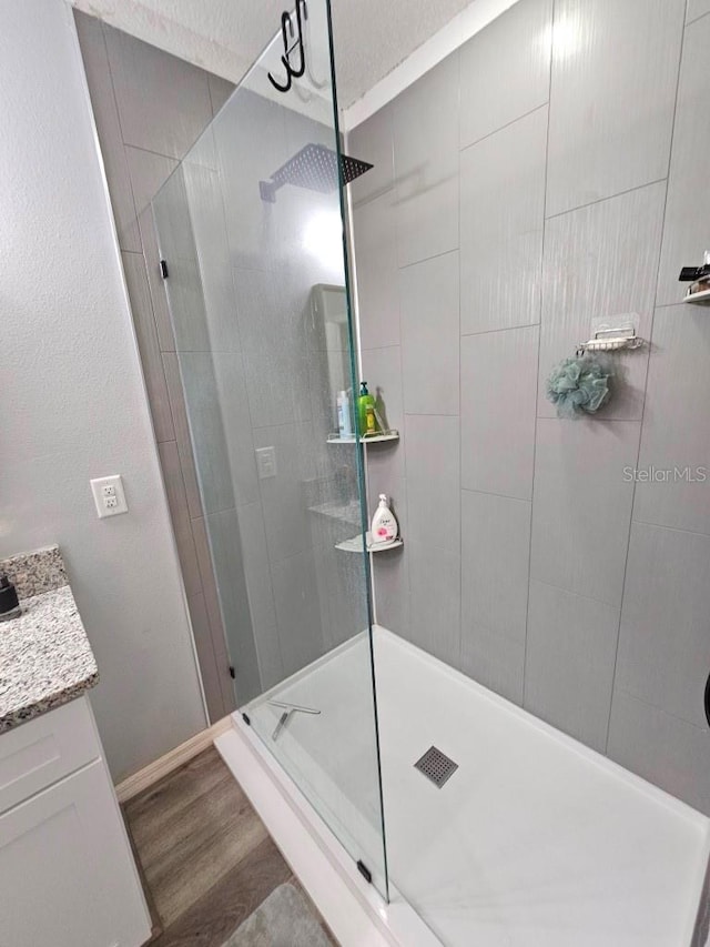 bathroom with vanity, hardwood / wood-style floors, and tiled shower