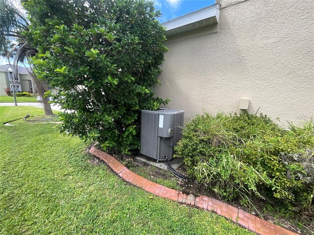 view of side of property with a lawn and cooling unit