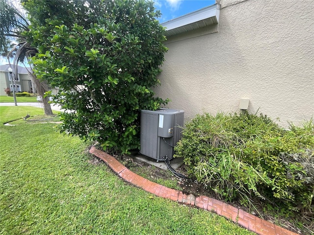 view of side of home featuring central AC unit and a yard