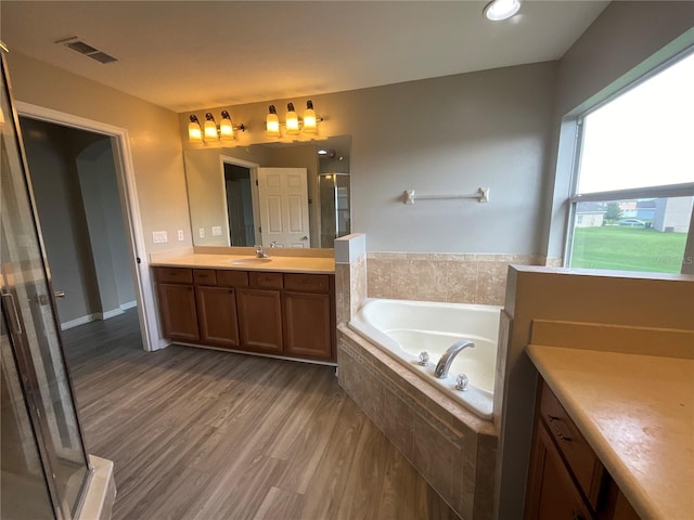 bathroom featuring wood-type flooring, vanity, and separate shower and tub