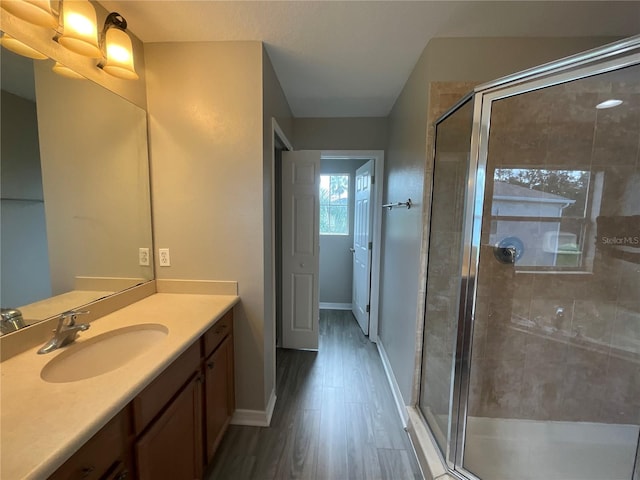 bathroom with wood-type flooring, a shower with door, and vanity