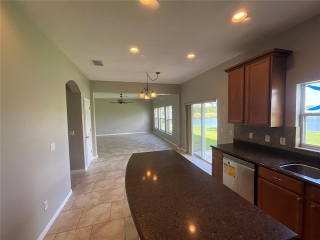 kitchen featuring dark stone counters, a healthy amount of sunlight, stainless steel dishwasher, and ceiling fan