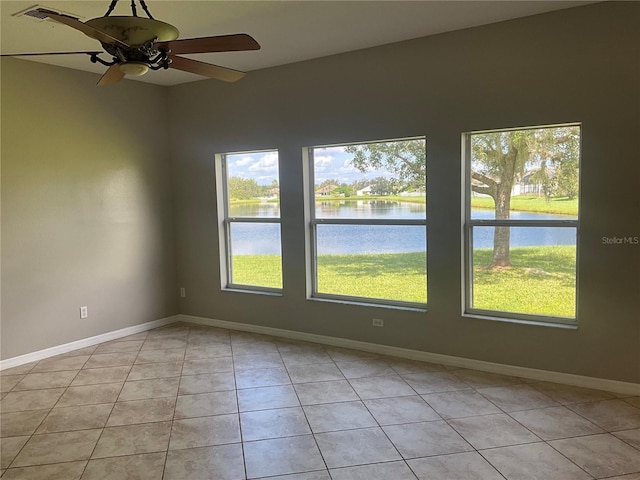 spare room with a water view, ceiling fan, and light tile patterned floors