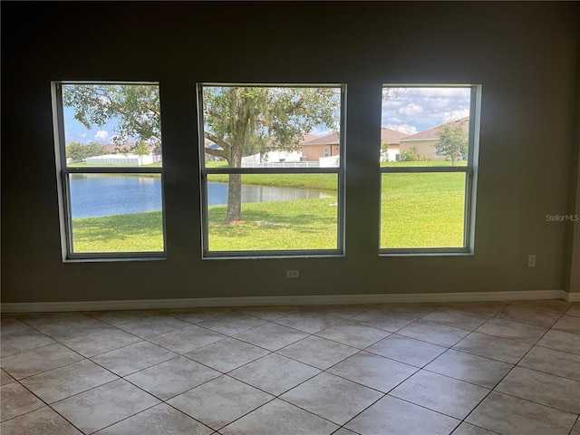 empty room with a water view, plenty of natural light, and light tile patterned flooring